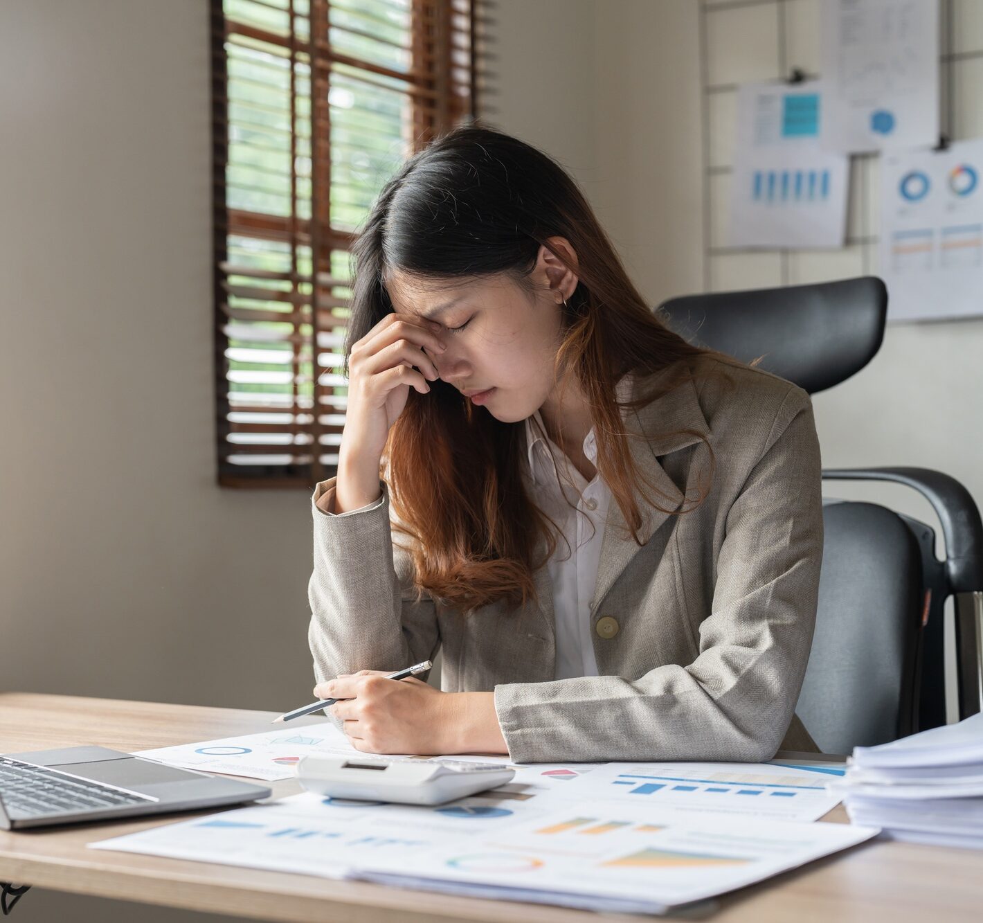 Upset woman touching head using calculator and laptop for calculating finance. Frustration young